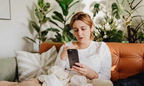 Jeune femme parlant au t&eacute;l&eacute;phone en visio.