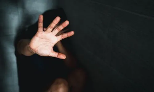 Gros plan sur la main d’une personne recroquevillée qui fait un signe « stop ».